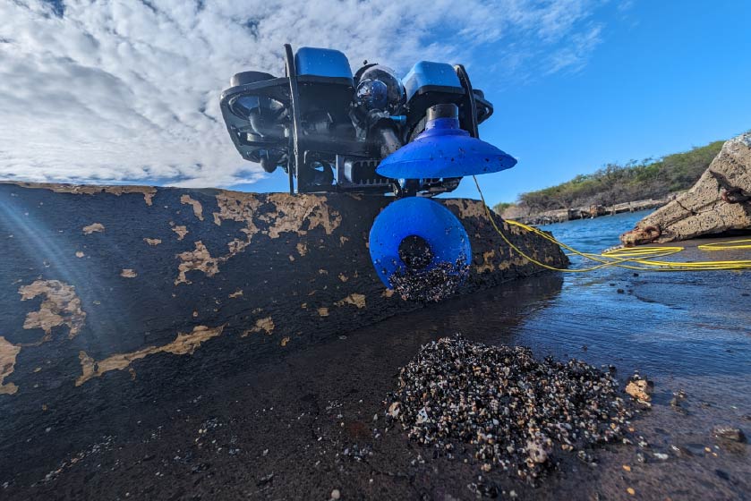 BlueROV2 with Newtown Sediment Sampler dropping a sample of sand on a rock out of the water